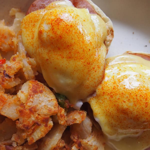 Eggs Benedict with hollandaise sauce and paprika, served with crispy hash browns at Offshore Diner.